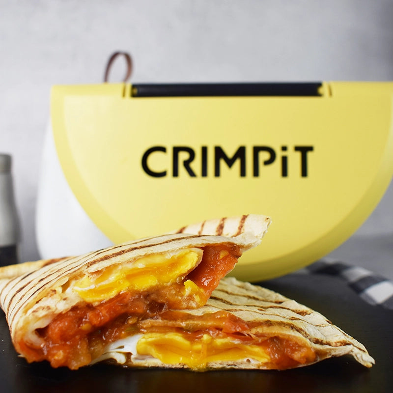 A cooked tortilla with egg and tomato filling with a CRIMPiT Tortilla Sealer behind.