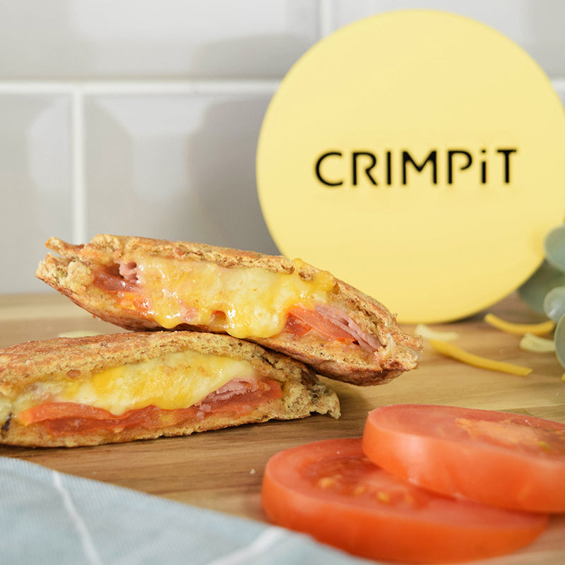A toasted snack with ham, tomato and cheese filling on a table with the CRIMPiT Circle. 